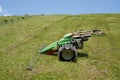 Green grass cutter or lawnmower as single-axle walk-behind tractor with special tire for steep slopes.