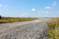 Green grass and farmlands below. A bright, sunny day. Gravel path in the fields under blue sky with clouds before sunset