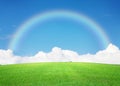 Green grass field, blue sky with clouds on horizon and rainbow Royalty Free Stock Photo