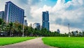 Green grass field, pedestrian road and coconut trees at the city park beside the sea. Royalty Free Stock Photo