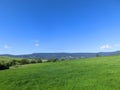 Green grass field on small hills and blue sky with clouds Royalty Free Stock Photo