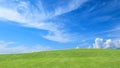 Green grass field on small hills and blue sky with clouds for background Royalty Free Stock Photo