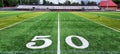 Green Grass Football Field with Yard Number Fifty with stands in the background Royalty Free Stock Photo