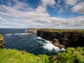 Green grass grows on edge of a cliff by the ocean. Ireland, Kilkee area. Travel, tourism and sightseeing concept. Irish landscape