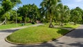 Green grass lawn garden by walkway, seating chair under palm tree in park Royalty Free Stock Photo