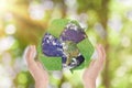 Green grass recycle symbol and Earth in hands over green nature background