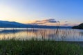 Green grass by shore of quiet Lake Kussharo in Hokkaido, Japan at sunset Royalty Free Stock Photo