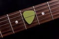 Green guitar pick on the fingerboard Royalty Free Stock Photo