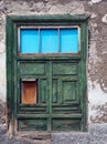 Green half shuttered old shabby window in a decaying house Royalty Free Stock Photo