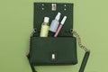 Green hand bag with  lip gloss and antiseptic on green background. Green monochrome Royalty Free Stock Photo