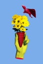 Green hand holding fresh yellow daisy flowers surreal collage with flying red bat demon animal spooky image isolated on