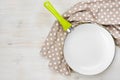 Green handle frying pan and kitchen towel over wooden background Royalty Free Stock Photo