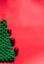 Green handmade knitted Christmas tree with small shiny red balls. Christmas toy. Beautiful red gradient Christmas background and