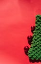 Green handmade knitted Christmas tree with small shiny red balls. Christmas toy. Beautiful red gradient Christmas background and