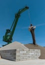 Green harbor crane pours sand and gravel onto a hill