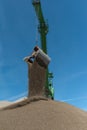 Green harbor crane pours sand and gravel onto a hill