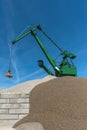 Green harbor crane pours sand and gravel onto a hill