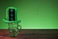 Green hat on empty beer glass. Green background. Saint Patrick theme background. Copy space