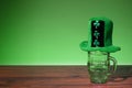 Green hat on empty beer glass. Green background. Saint Patrick theme background. Copy space