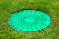 Green hatch of a sewer system in a clearing with green grass. Royalty Free Stock Photo