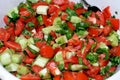 Green healthy organic freshly cut salad of fresh vegetables pieces and slices of tomatoes, cucumber, arugula leaves and onion with Royalty Free Stock Photo