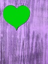 The green heart is carved in a wooden board of purple. Background. Royalty Free Stock Photo