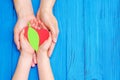 Green heart in hands of adult and child Royalty Free Stock Photo
