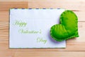 Green heart on natural wooden table on Valentine`s Day