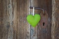 Green heart shape hanging on door handle - wooden background wit