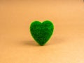 Green heart shaped ball covered with grass isolated on brown recycled paper background.