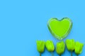 Green heart and tulips on a turquoise background, fragile love background, creative valentines day concept Royalty Free Stock Photo