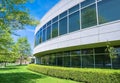 Green hedge and mowed lawn along round shaped wall of the office building Royalty Free Stock Photo