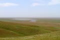 Green hills in the steppe at spring time and a lake in a distance