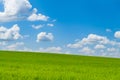 Green hillside under blue sky with beautiful clouds Royalty Free Stock Photo