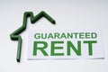 Green House Model And Paper With Guaranteed Rent Text