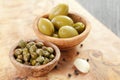 Green huge olives and capers on wood table