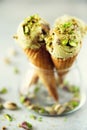 Green ice cream in waffle cone with chocolate and pistachio nuts on grey stone background. Summer food concept, copy Royalty Free Stock Photo