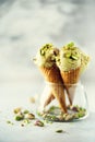 Green ice cream in waffle cone with chocolate and pistachio nuts on grey stone background. Summer food concept, copy Royalty Free Stock Photo