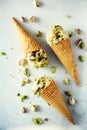 Green ice cream in waffle cone with chocolate and pistachio nuts on grey stone background. Summer food concept, copy Royalty Free Stock Photo