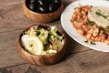 Green iceberg lettuce salad with cucumbers, radishes, sunflower seeds, lemon and parmesan. Behind, in defokus chicken with rice Royalty Free Stock Photo