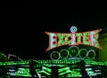 Green illuminated fairground ride with a red outline Exciter sign on the night background