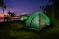 Green illuminated from inside tent above river at sunset. Royalty Free Stock Photo