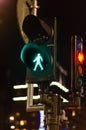 Green illuminated pedestrian crossing signal on top of a street sign at night Royalty Free Stock Photo