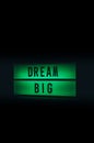 Green illuminated sign with dream big written on it