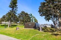 A green iron statue of a sailor at the wheel surrounded by lush green grass and trees with blue sky at Burton Chace Park Royalty Free Stock Photo