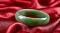 Green jade bangle on luxurious red satin fabric. Royalty Free Stock Photo