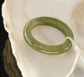 A Green Jade Ring with a White Yarn on a White Shell Background Royalty Free Stock Photo