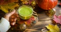 Green Japanese matcha tea with foam in transparent Cup on wooden table in autumn still life. Women`s hand with long white sweater