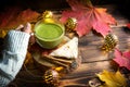 Green Japanese matcha tea with foam in transparent Cup on wooden table in autumn still life. Women`s hand with long white sweater