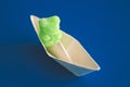 Green jelly gummy bear in paper boat on blue background. Royalty Free Stock Photo